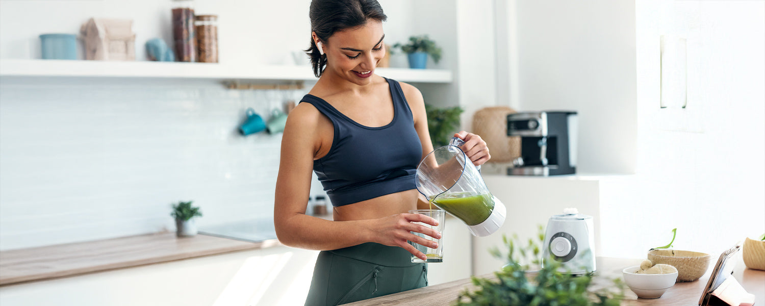 Woman in activewear preparing a healthy green smoothie at home