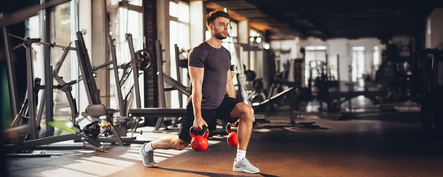 Man doing lunges with kettlebells at the gym